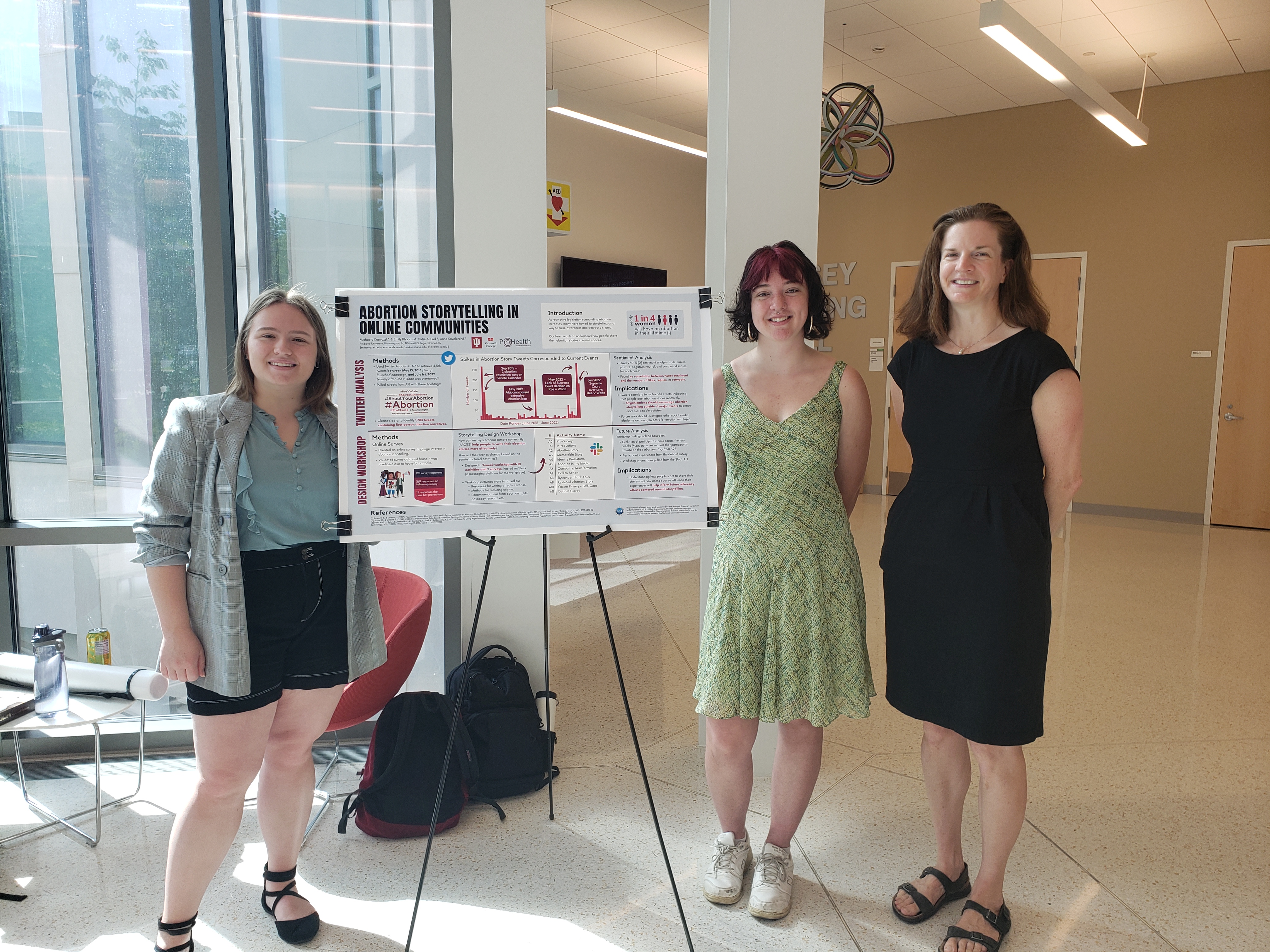 Michaela Krawczyk, Emily Rhoades, and Katie Siek standing next to their abortion storytelling poster during the ProHealth REU gallery.